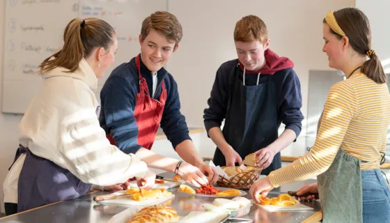 Fire ungdommer som lager mat på skolekjøkkenet.
