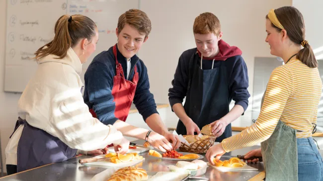 Fire ungdommer som lager mat på skolekjøkkenet.