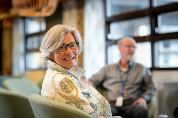 Portrett av rektor Gro Kristiansen inne på lærerværelset på Dalgård skole og ressurssenter. I bakgrunnen skimtes en kollega.