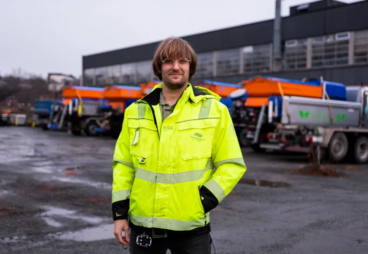 Foto av miljørådgiver Markus Karijord. I bakgrunnen ser vi et garasjeanlegg og noen lastebiler.