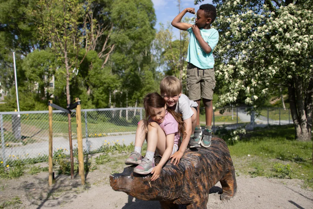 Tre barn på en figur av en bjørn.