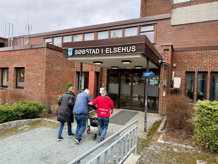 Frivillige geleider en pasient inn døra til Søbstad helsehus