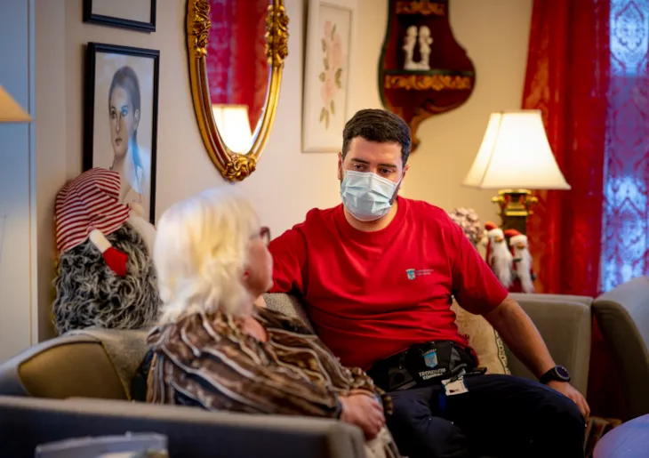 Malik sitter i en sofa sammen med en pasient. Hun er vendt bort fra kamera. De har en samtale.
