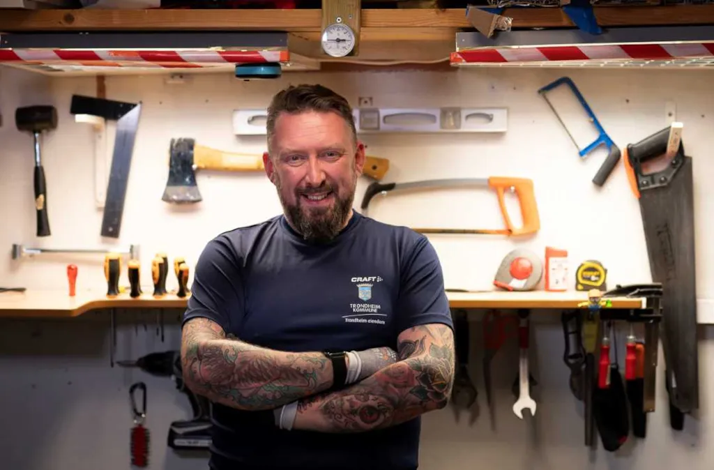 Driftsoperatør Kim Roger Olsen står foran verktøybenken med ansiktet vendt mot kameraet. I bakgrunnen ser vi verktøy som henger på veggen.
