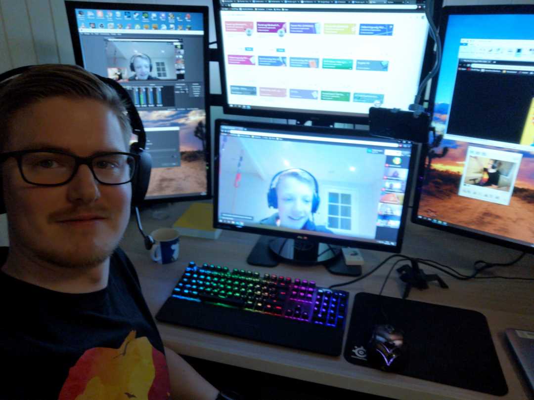 Bilde av ungdomsskolelærer Ola Fossum foran pcn med fire skjermer. På skjermene ser vi bilder av elevene som han underviser hjemmefra.