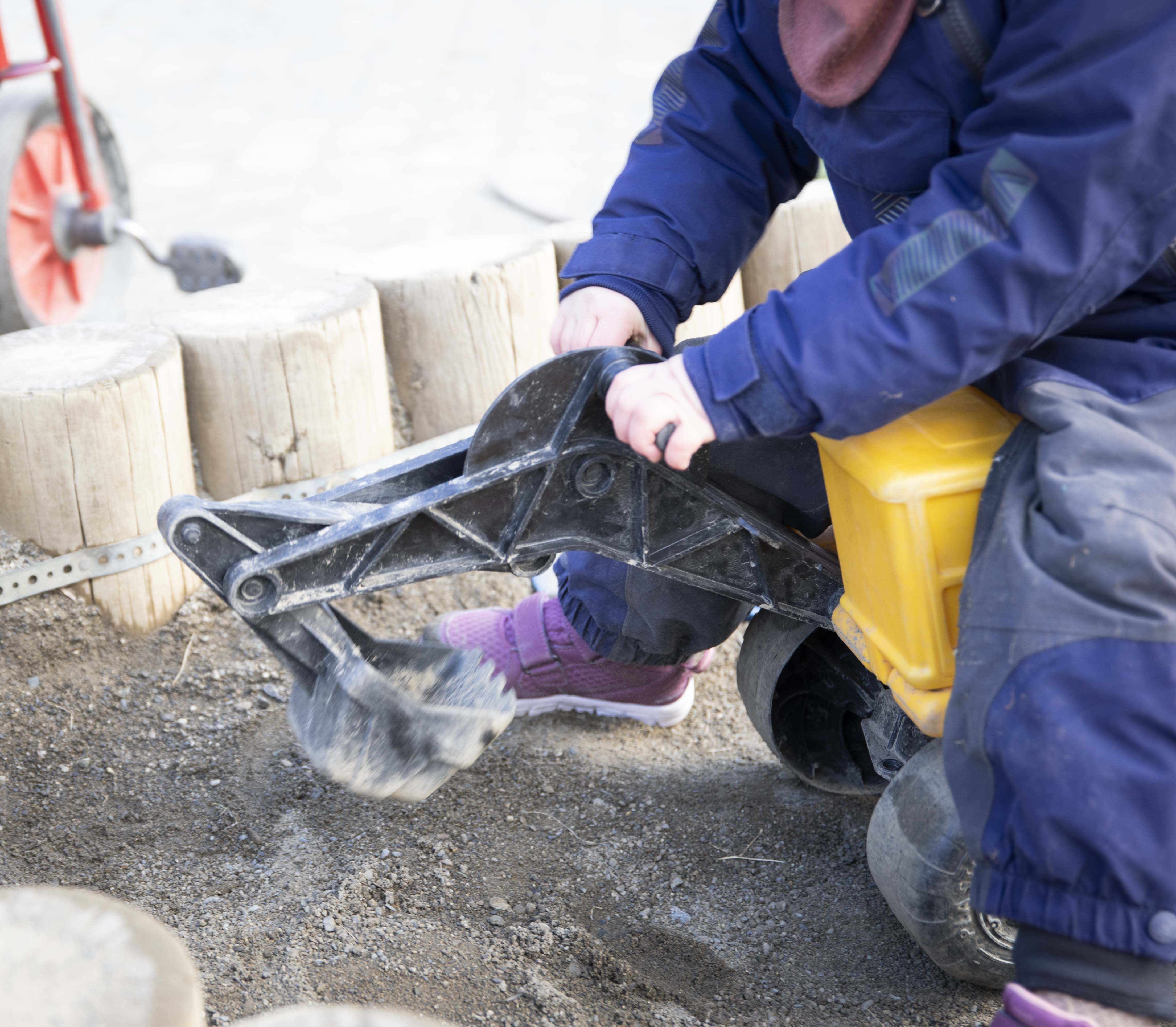 Barn med lekegravemaskin i sandkassa