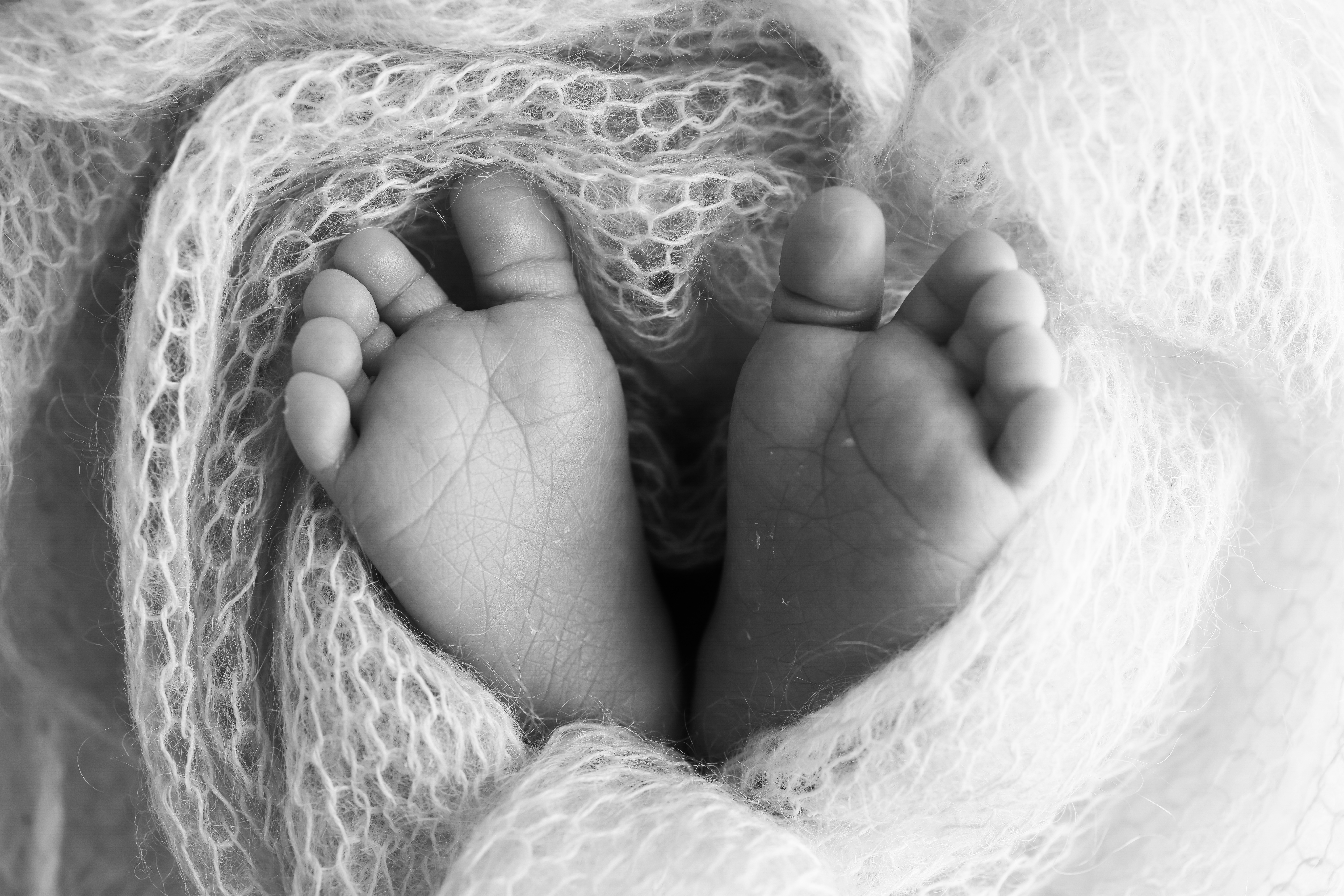 To føtter til en liten baby som stikker ut av et heklet pledd