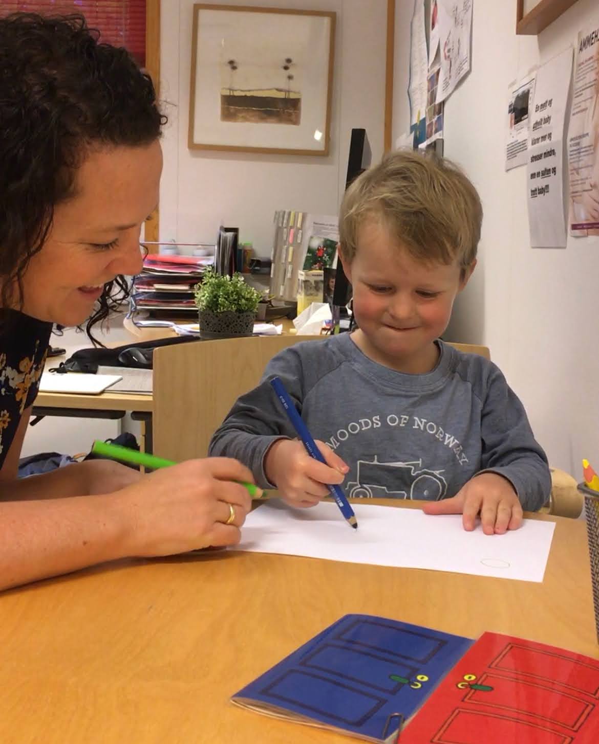 Et barn og en voksen tegner med blyant