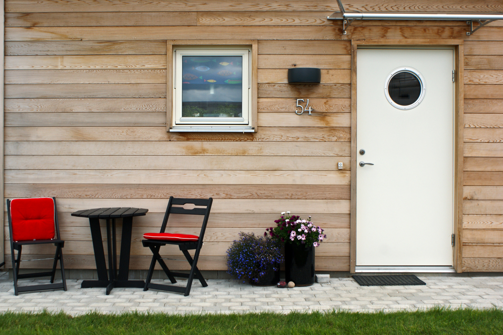 husvegg med dør, blomsterpotte og utemøbler