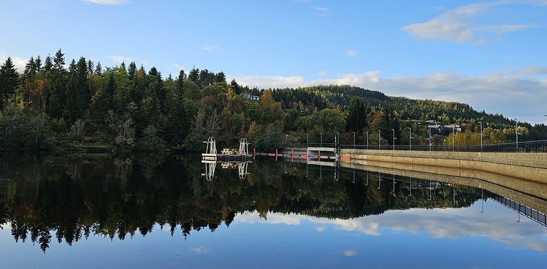Foto av badebrygge på Theisendammen med demning i bakgrunnen