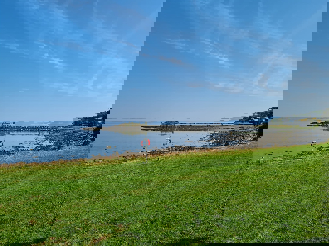 Gressplen med redningsbøye foran fjorden