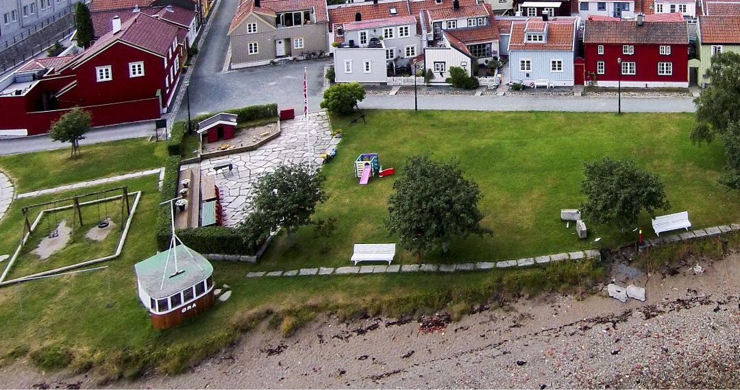 Oversiktsbilde med dissestativ og et båthus ved stranda