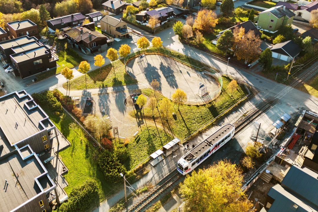 Oversiktsbilde over lekepark med trikk som står ved trikkeholdeplass