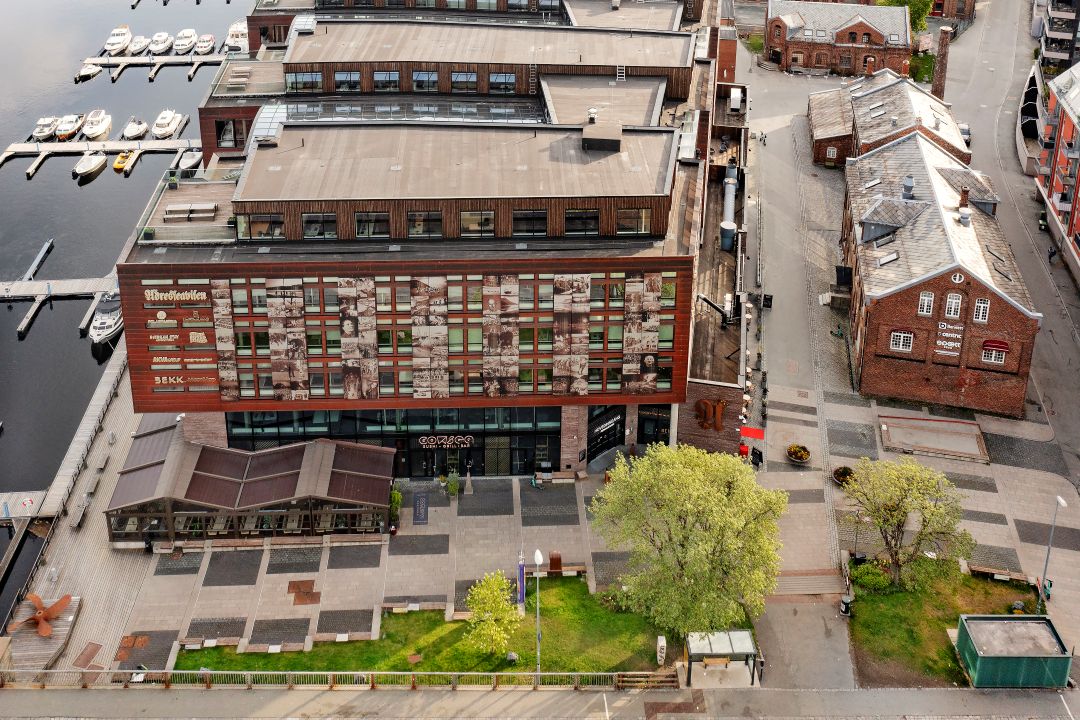 Dronebilde over smal park foran kontorbygning