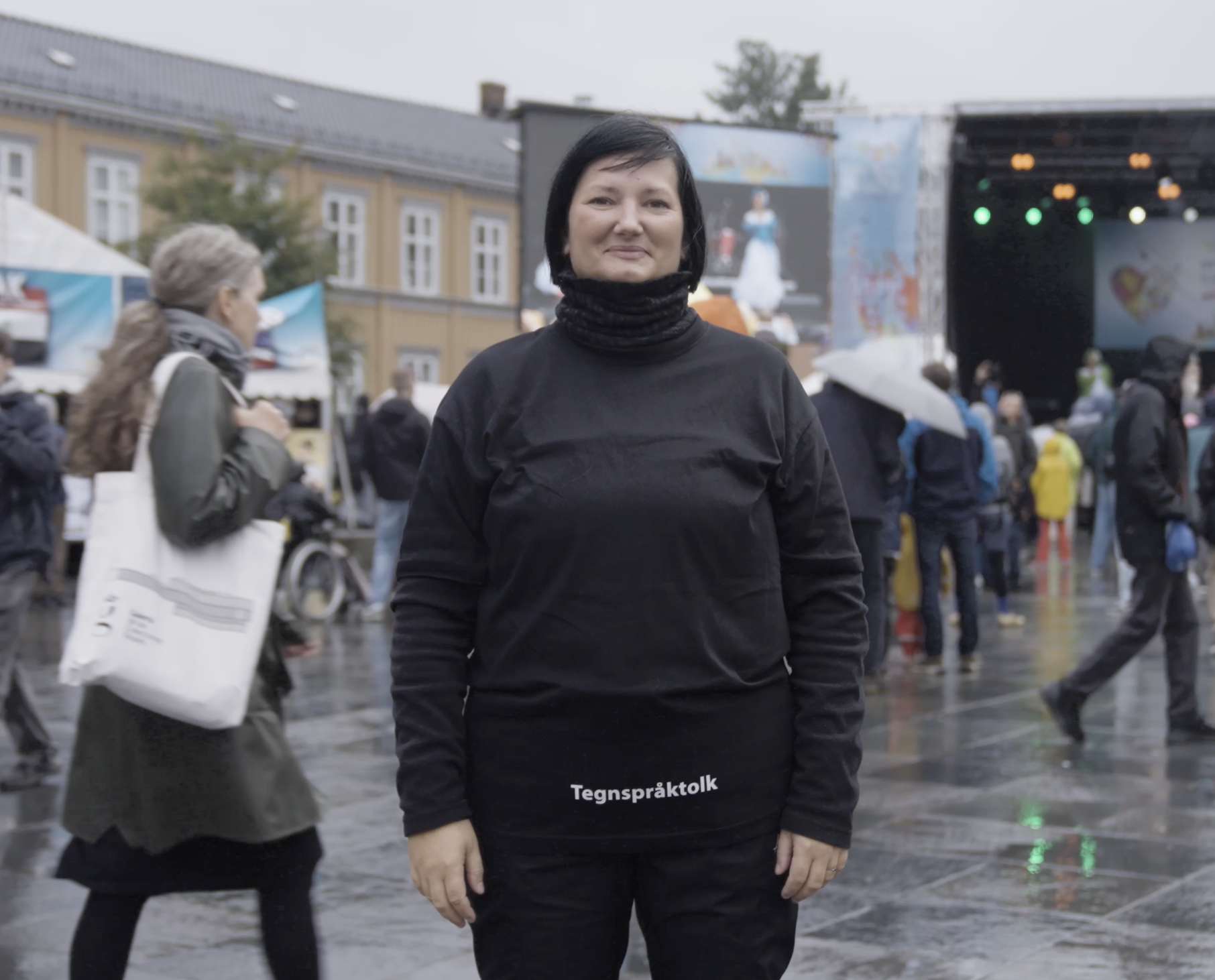 Kvinne som står med svart genser hvor det er skrevet "tegnspårktolk"