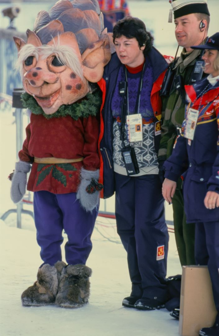 En maskot med hode som ligner en kongle, st&aring;r sammen med tre personer