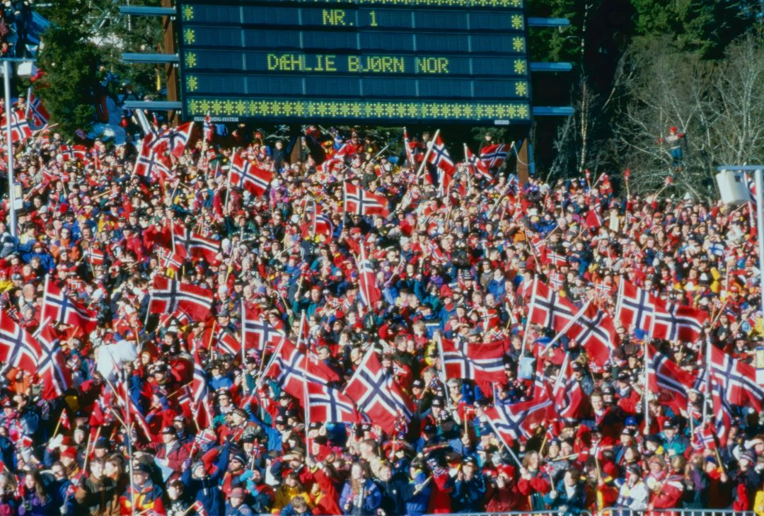 Publikum med norske flagg og en tavle som viser navnet Bjørn Dahlie som vinner