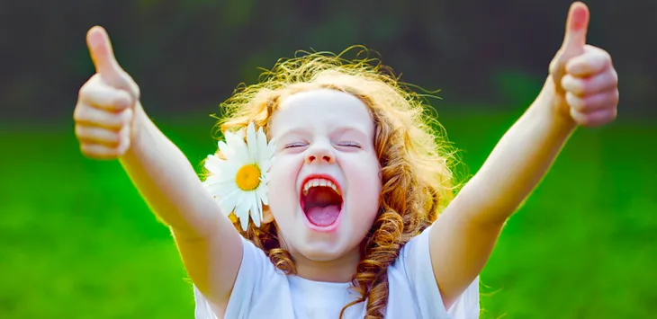 Leende jente med tomler opp