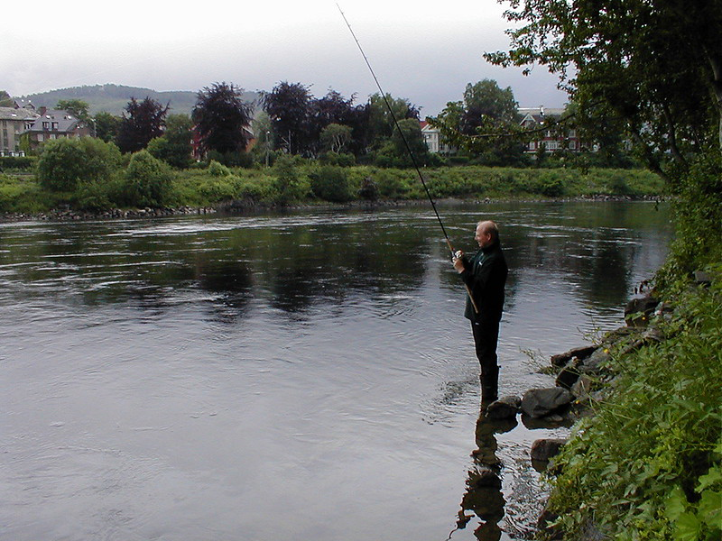 Mann som st&aring;r &aring; fikser i en elv