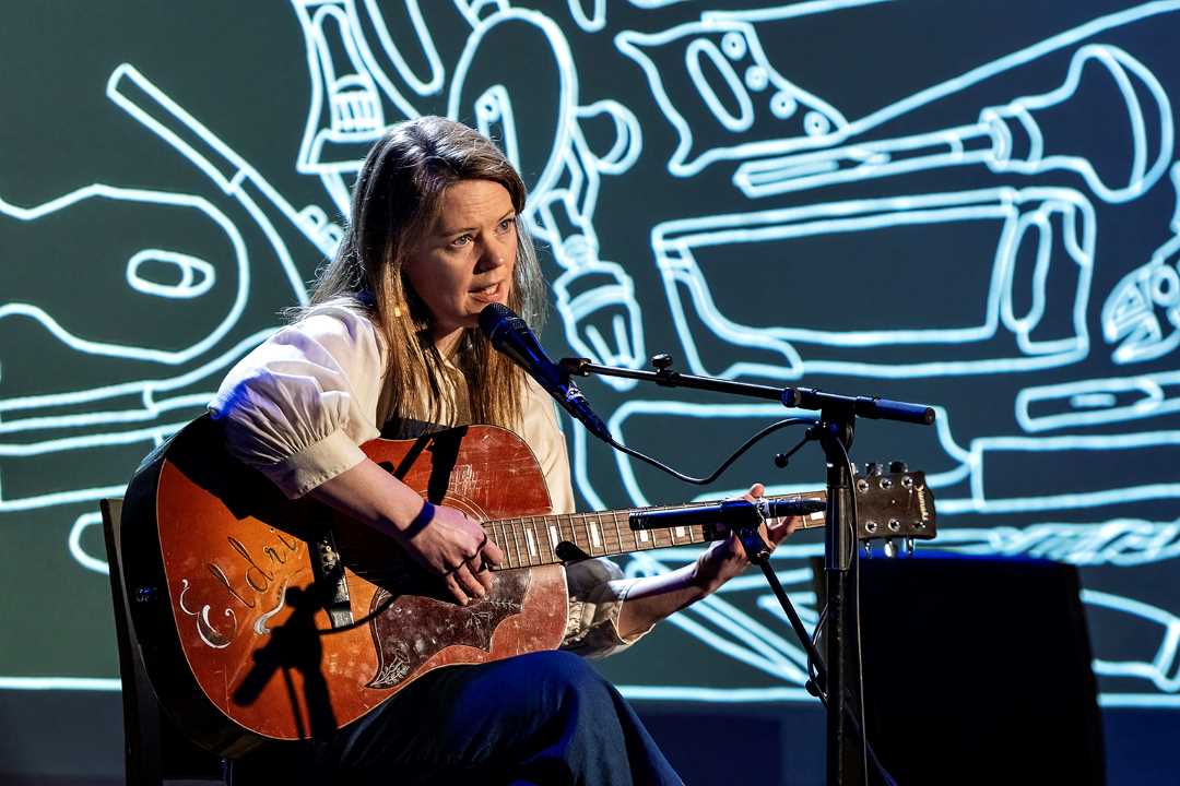 Dame som sitter og spiller gitar