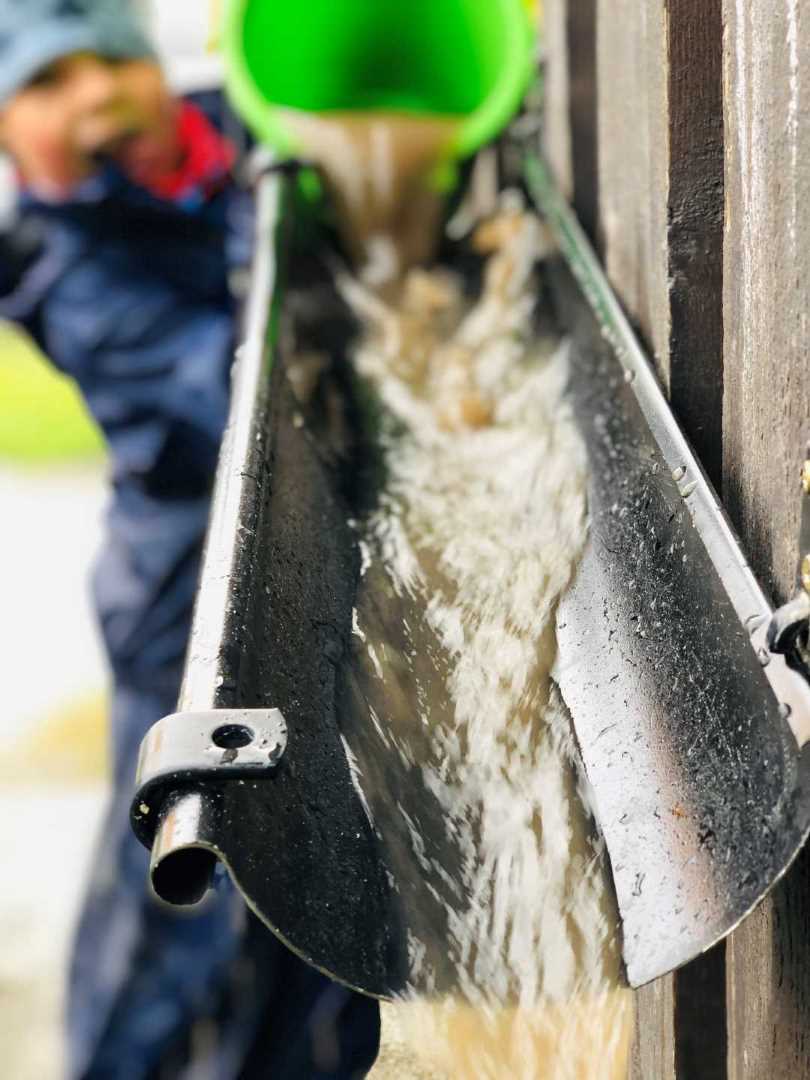 Barn som t&oslash;mmer vann i en renne