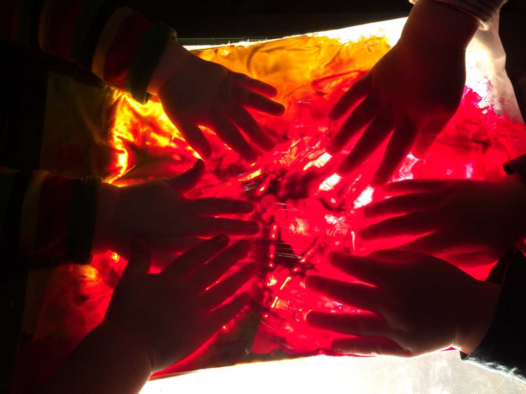 Sm&aring;barn maler p&aring; gjennomsiktig underlag p&aring; lysbord