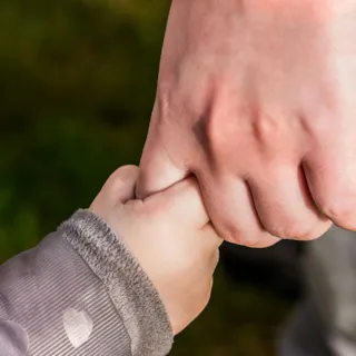 En liten hånd holder rundt en voksen finger