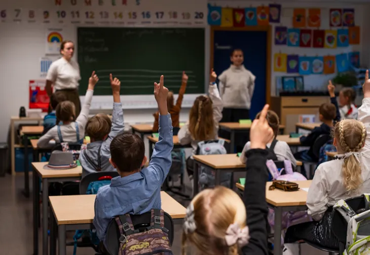 Bildet viser elevene i 1. klasse som rekker opp hånden for å svare på spørsmål.