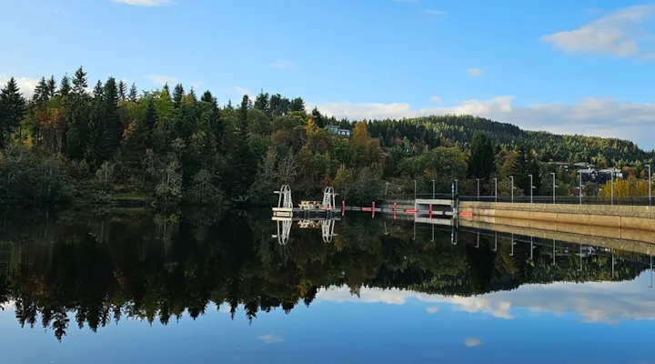 Foto av badebrygge på Theisendammen med demning i bakgrunnen