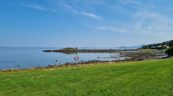 Gressplen med redningsbøye foran fjorden