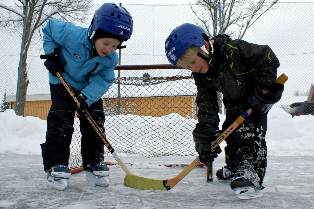 To gutter spiller ishockey med skøyter, kølle og hjelm