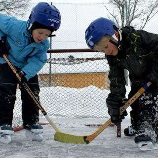 To gutter spiller ishockey med skøyter, kølle og hjelm