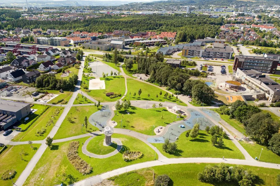 Dronebilde over stor park med lekeområder og grønne plener.