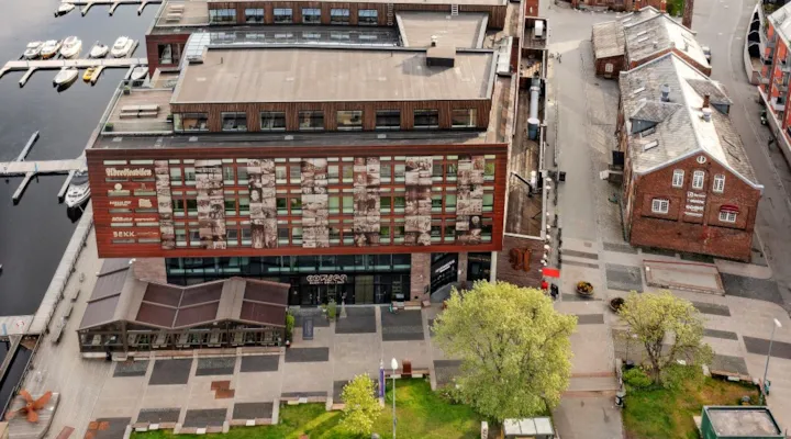 Dronebilde over smal park foran kontorbygning