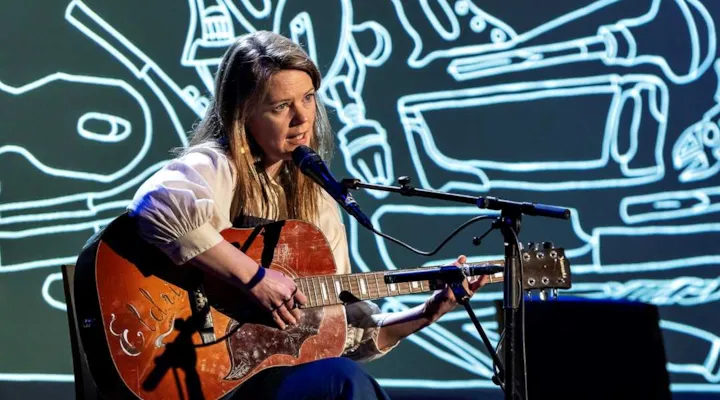 Dame som sitter og spiller gitar