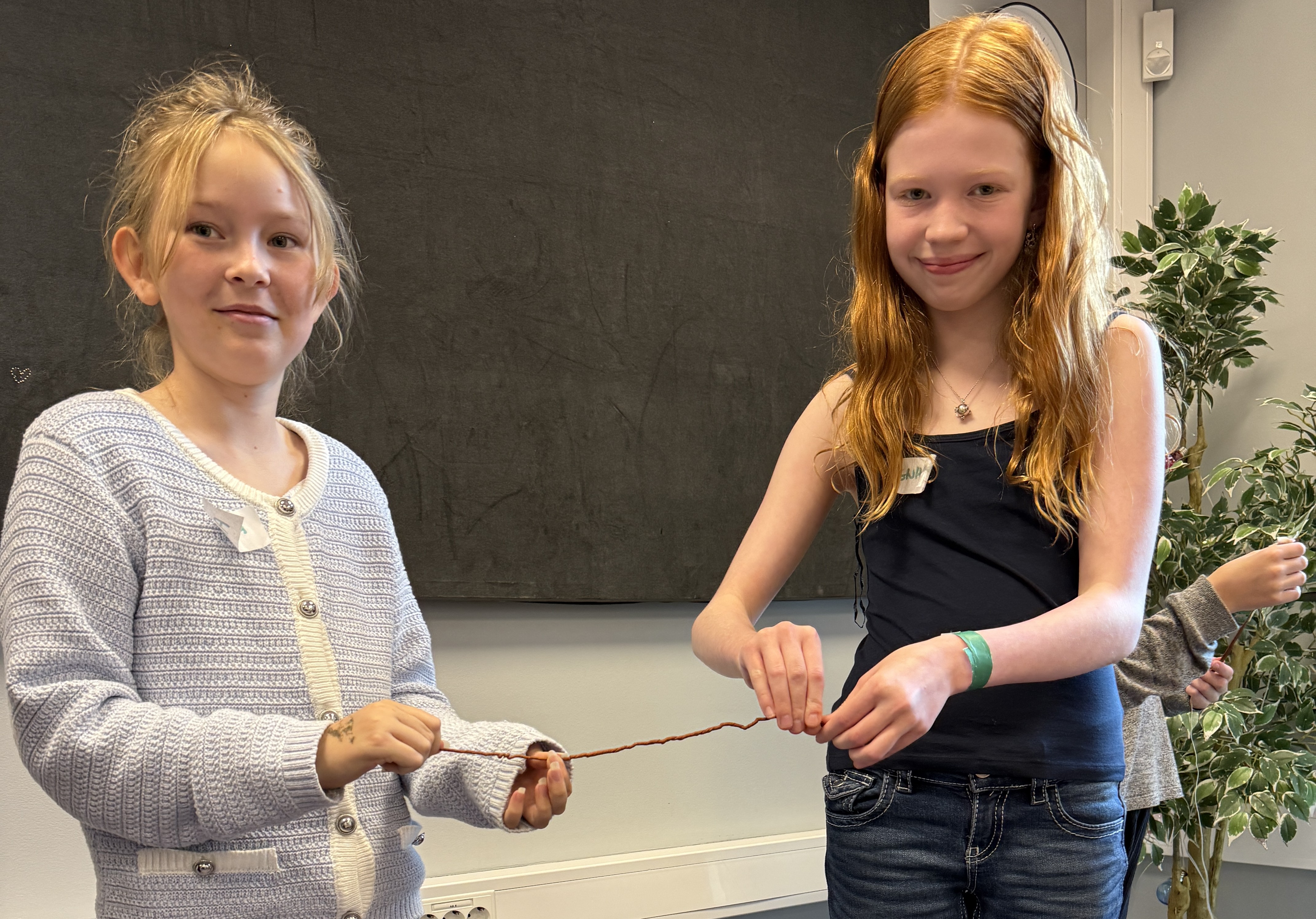 To jenter samarbeider om å lage snurrearmbånd