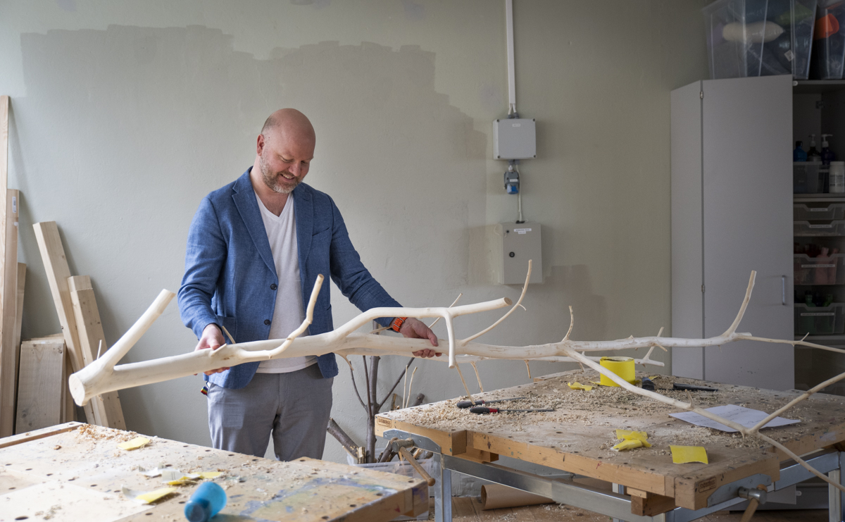 Rektor i sl&oslash;ydsalen med stamme som skal bli til et kunstverk.