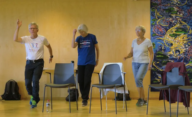 Tre personer som gjør treningsøvelser ved stol