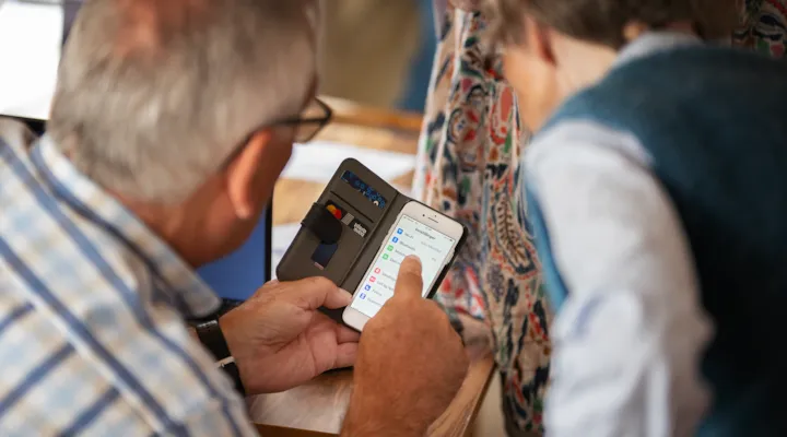 Eldre mann veileder eldre dame i bruk av smarttelefon