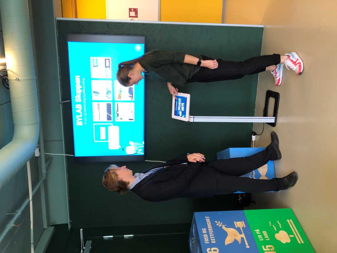 To personer st&aring;r foran en skjerm inne p&aring; bylab Sluppen