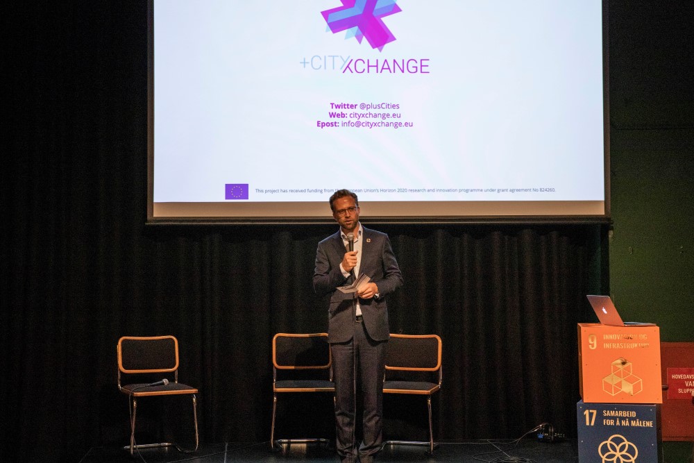 Kommunal og moderniseringsminister Nikolai Astrup p&aring; scenen med +CityxChangelogoen bak seg