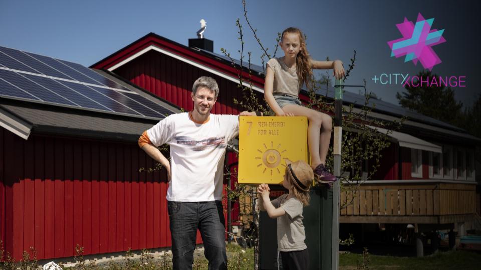 Bilde av far og to barn foran et hus med solceller på taket. De holder i bærekraftsmål 7, ren energi for alle.