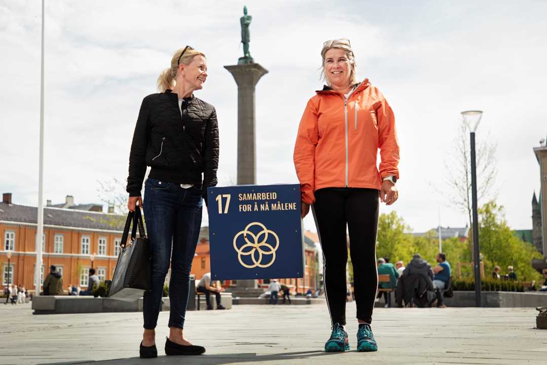 Foto av to kvinner som holder FNs bærekraftsmål nummer 17 - Samarbeid for å nå målene