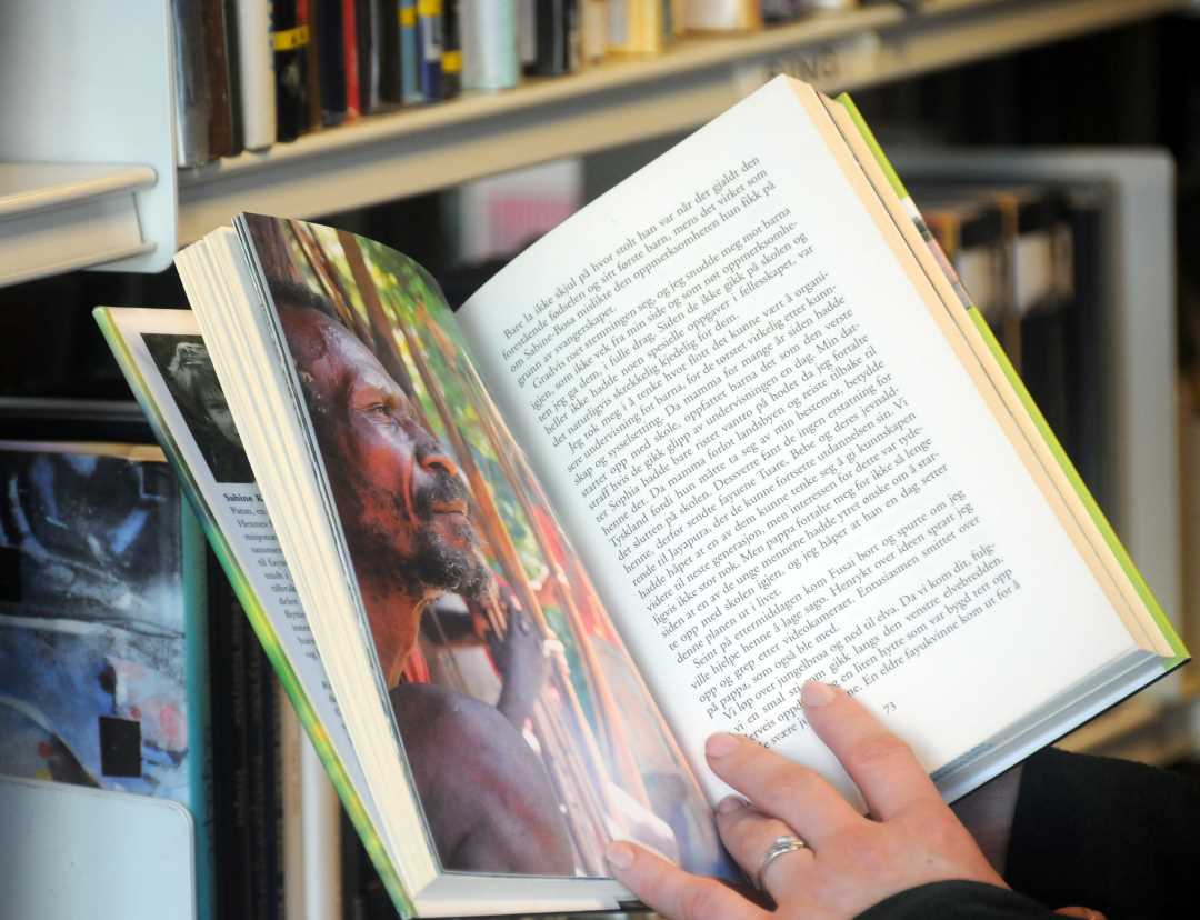 Bilde av noen som leser i ei bok på biblioteket