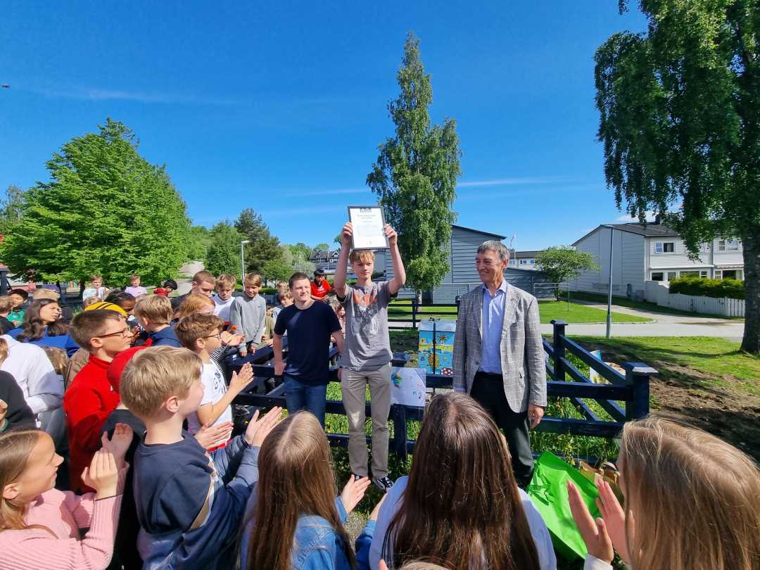 Elever ved Flatåsen skole mottar beviset på at skolen har fått Grønn Barnebys pris for 2022. Juryleder Geirmund Lykke overrakte prisen til elever på 10. trinn.